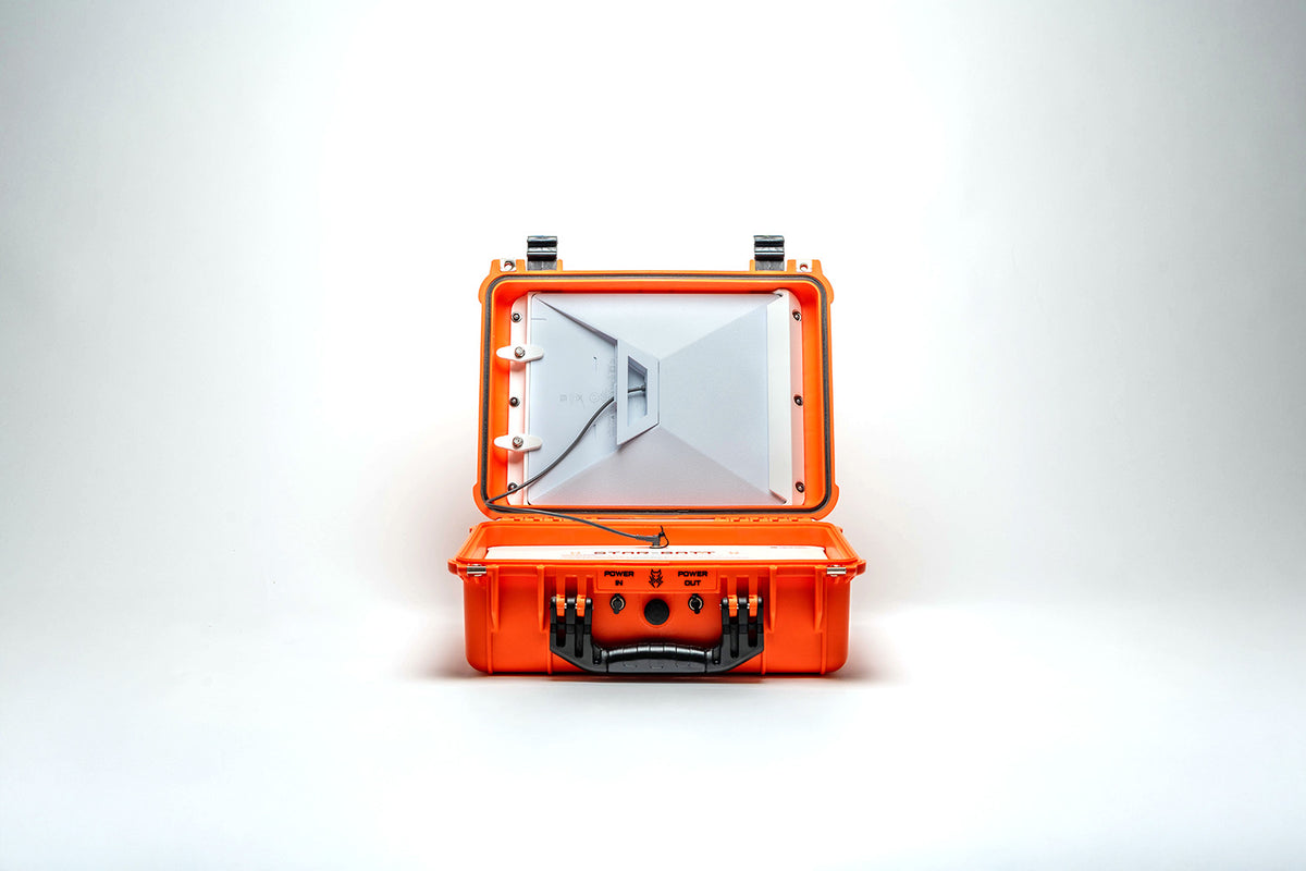 An orange hard-shell carrying case shown open, revealing a white interior with a folded panel or mat and black latches and handle details, photographed on a clean white studio background.